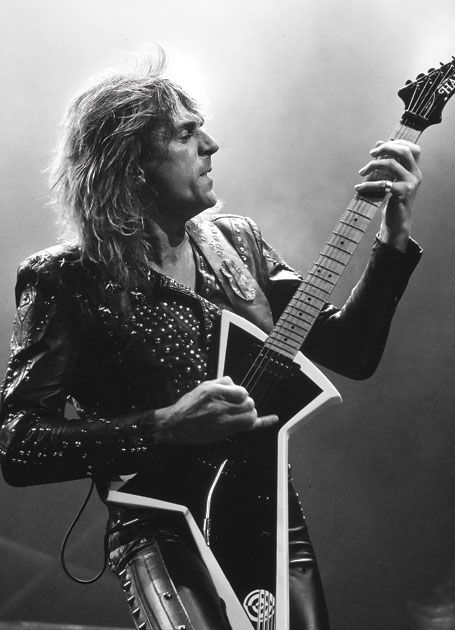 Here's a guitar that Hamer built for Judas Priest guitarist Glenn Tipton. It's a mix between an Explorer and a Dean ML guitar, but this one's different. You know how some of these guitars have a point on the body that you can whack your elbow on? Well, this guitar has a point as well, but it's on the bottom half of the body. This lets you use it to brace the guitar against your leg, as Glenn's doing in the picture. It's got two humbuckers, one volume control, a 3-way switch, and a Kahler locking trem.