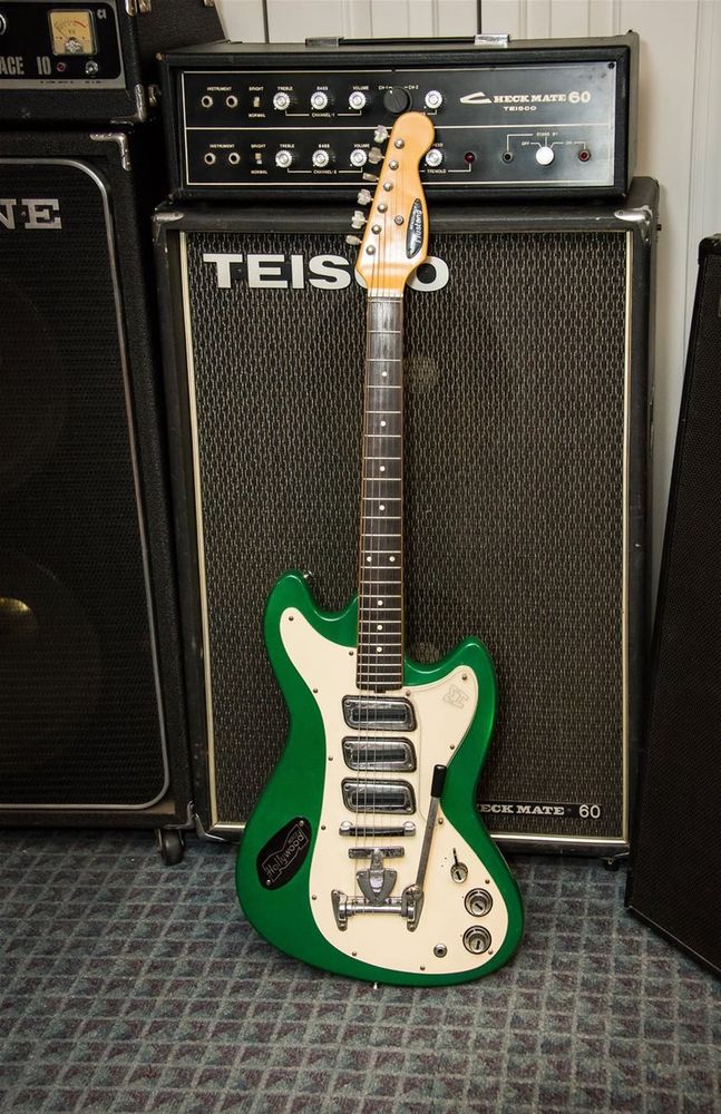 The Meazzi Hollywood Mustang was an Italian response to Fender's offset guitars. It's got three singe-coil pickups, one volume and one tone control, and a rotary pickup switch. All of the electronics are mounted on a large pickguard, as well as the tremolo/string mute combo. A large black plate with the company's logo is screwed into the guitar's green body, and a smaller one is on the 6-in-line headstock.