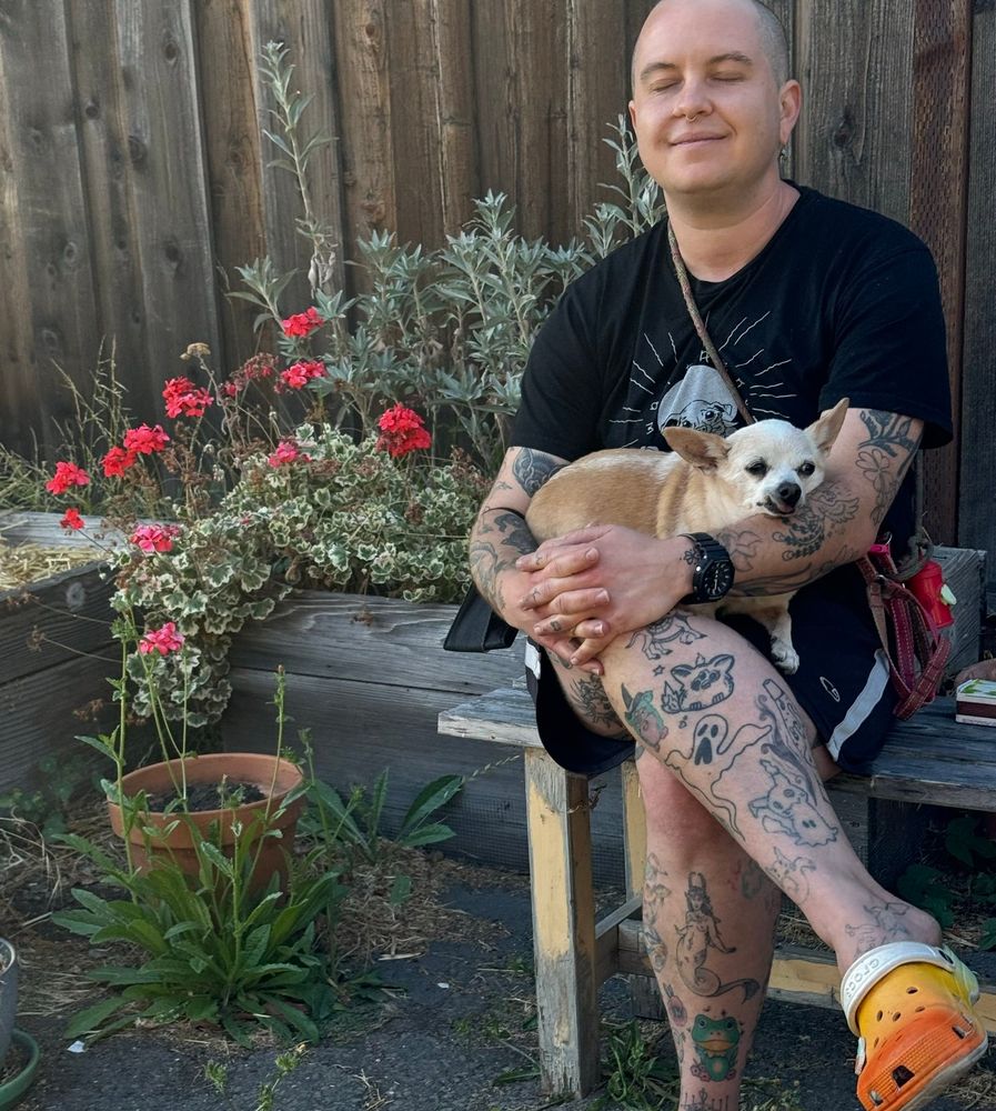 A picture of hax holding their dog Twinkle in his lap