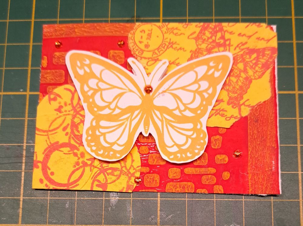1 atc im Mixed-Media-Stil 
Gleicher Untergrund wie vorher, darauf gelbe Papierfetzen, bestempelt mit Kreisen und Schriftzügen in rot. Darauf ein ockergelber Schmetterling 