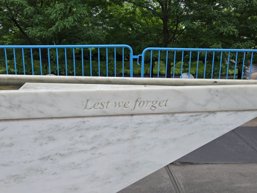 A portion of a marble monument resembling the prow of a ship, with the words, "Lest we forget"