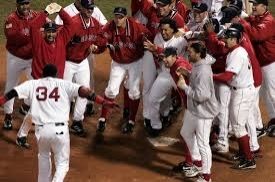 David Ortiz about to jump onto home plate, which is surrounded by celebrating teammates, after walking off game 4 of the 2004 ALCS to avoid a sweep by the Yankees