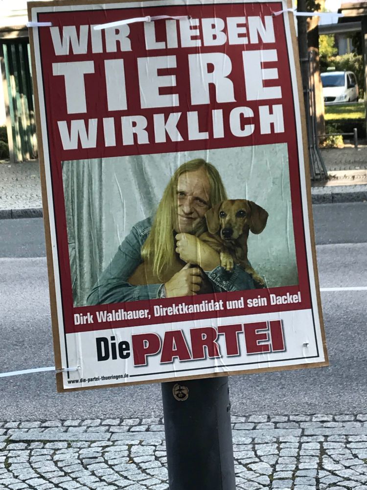 German political poster of long haired member of Die Partei and his dachshund.