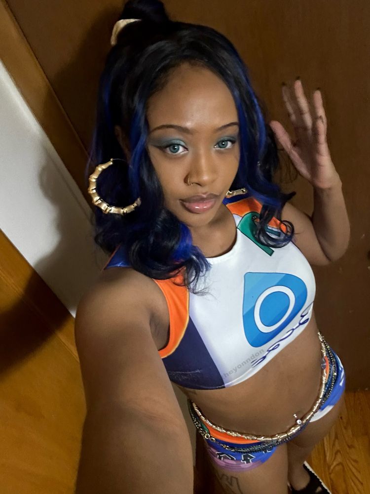 yonn dresssed as nessa from pokemon sword & shield game. golden hoop earrings peek from hair that frames yonn's face, the camera is angled so it looks downward at the cosplay.