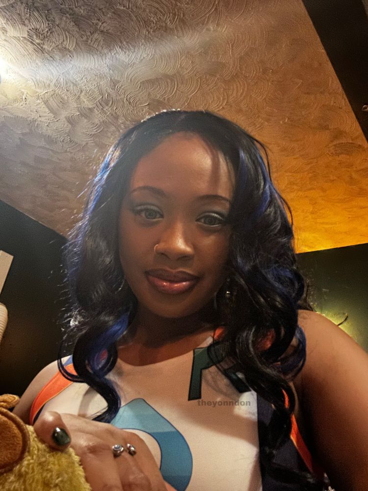 yonn in nessa from pokemon sword and shield game, looking downward towards camera with a slight smile. only shows yonn chest up and not full cosplay