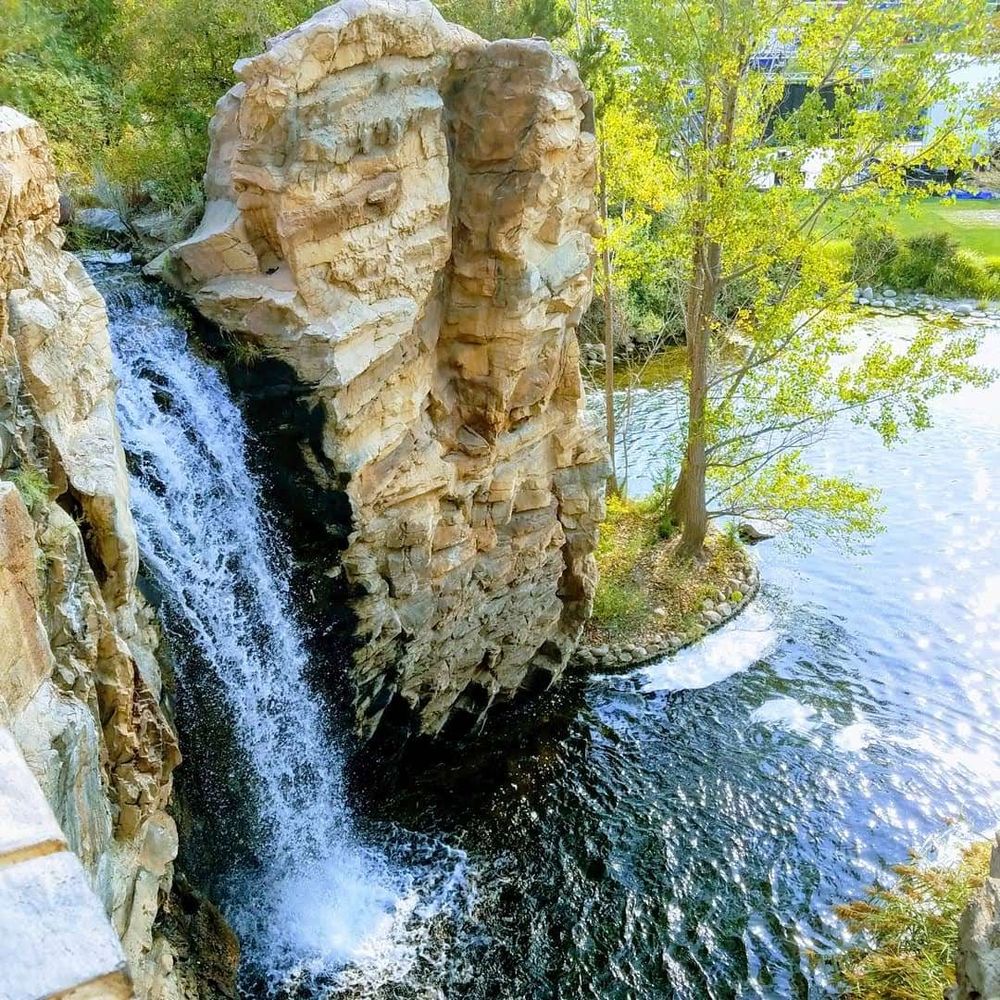 A waterfall leading down to a lake, with trees in the background.