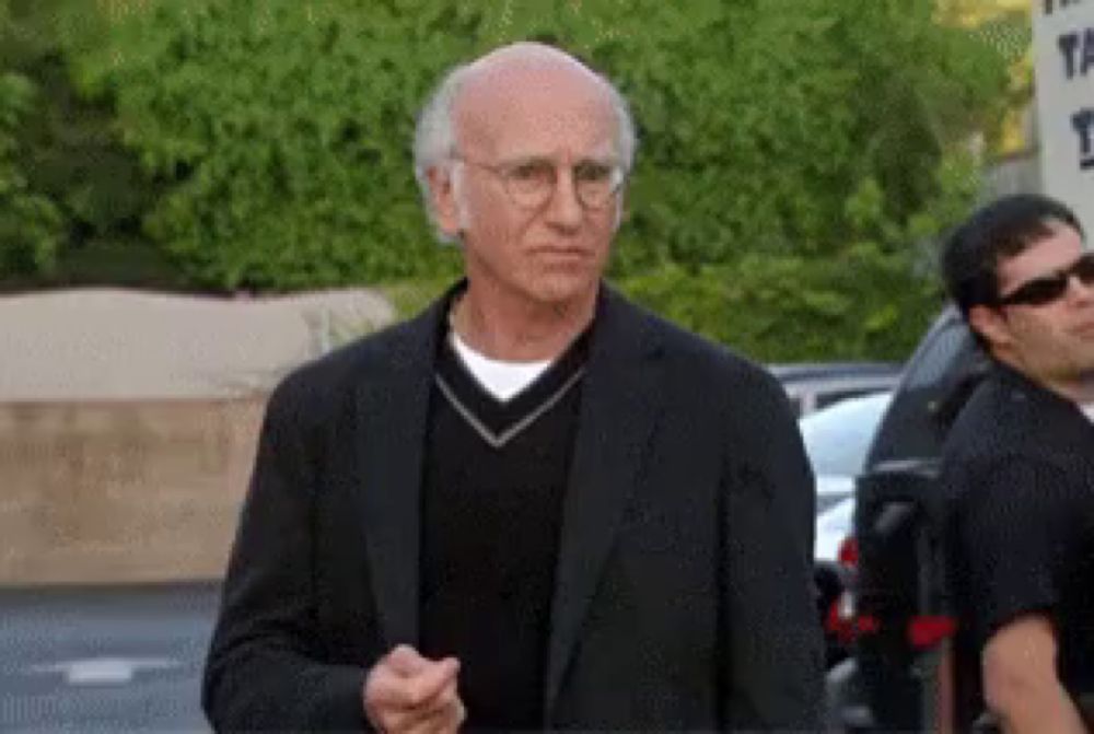 a man wearing glasses and a black suit is standing in front of a sign that says ' the ' on it