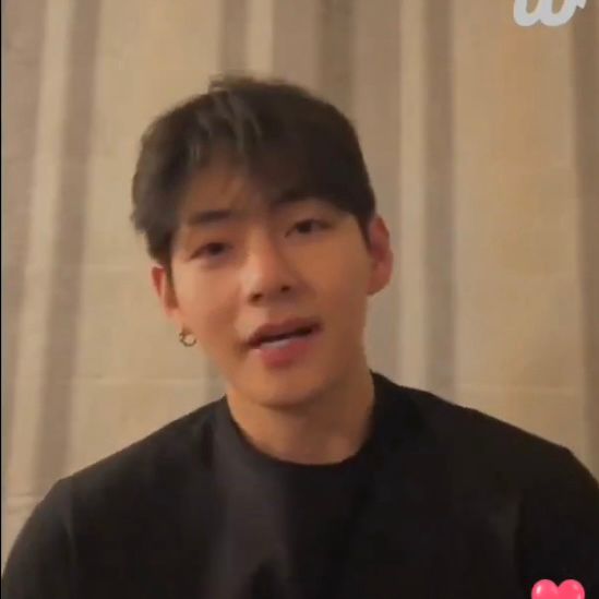 taehyung of bts in a black shirt speaking to the camera