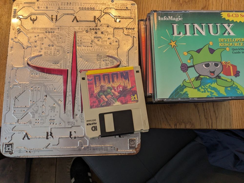 Image showing original Quake arena box, doom 1 diskettes and info magic CD-ROMs with Linux