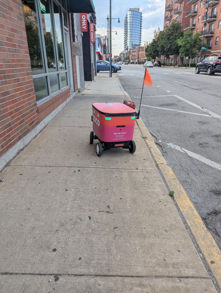 This robot was stopped just hanging out on the sidewalk. The sign says driven by humans so, I don't know why they seem like their stuck by the dumbest things. Maybe telepresence bots that go at walking speed and get stuck in bushes or at a gravelly curb are a dumb idea? 