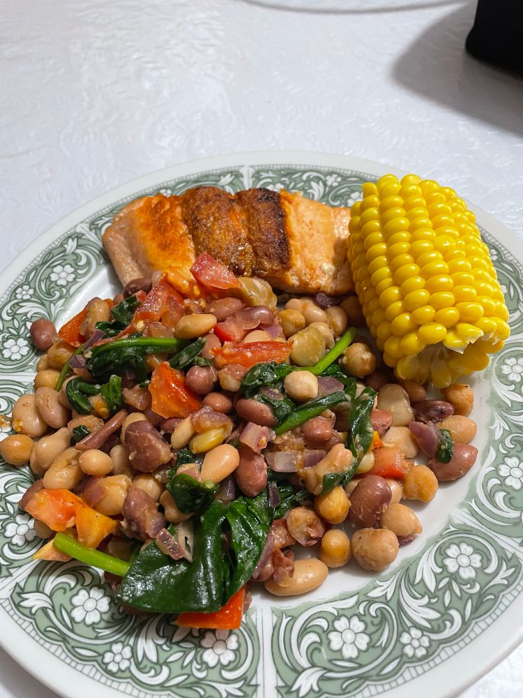 4 bean salad mix with steamed corn and crispy skin salmon on a plate 
