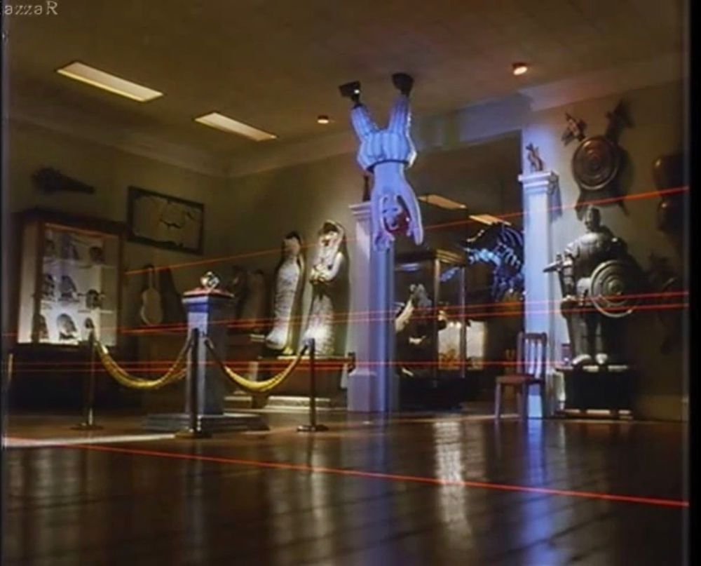 Scene from Wallace and Grommit. Wallace, wearing the automatic trousers, hanging from the ceiling in a museum, with lasers around. 