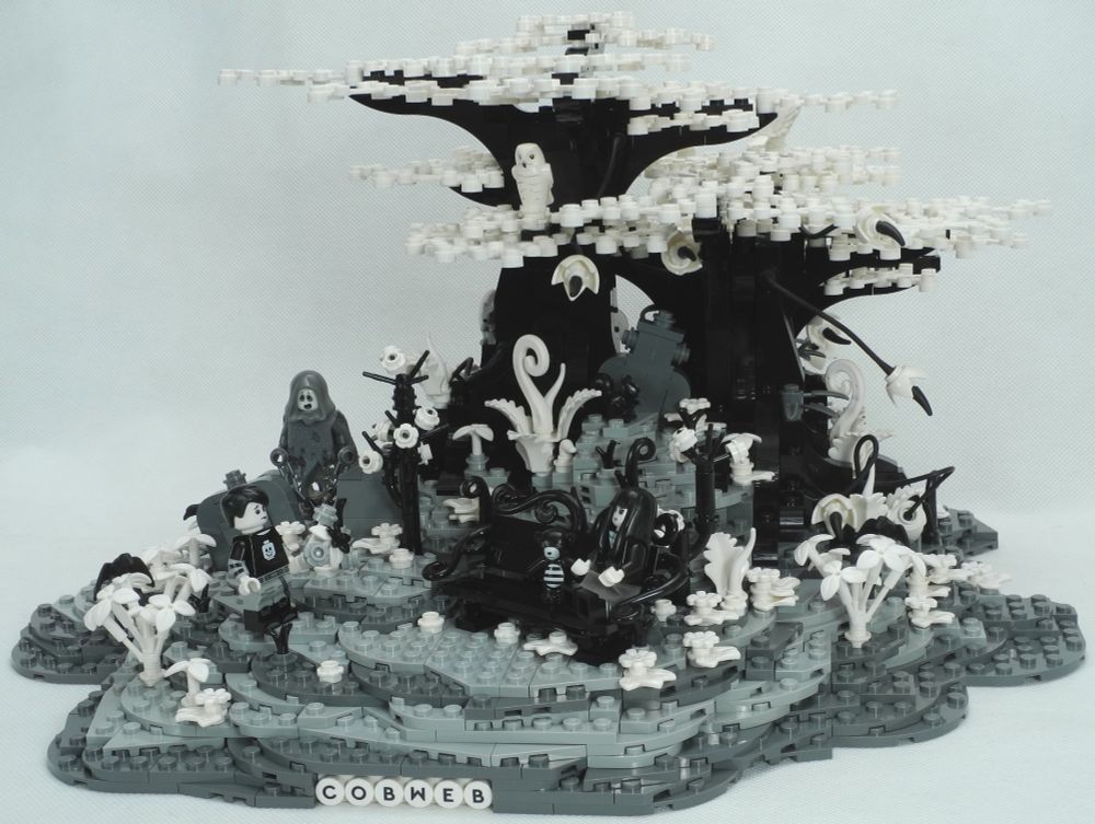 A smallish(ish) Lego diorama of an overgrown cemetery. There are several gravestones no longer upright and the plant-life has taken over somewhat. To the front of the scene a rather Wednesday Addams figure sits on an ornate bench, holding a distressed teddy bear in one hand, looking solemnly towards a similarly spooky boy who approaches with a nervous expression, bearing a bunch of flowers. The ground rises a little, in the background, into a knoll crowned by several gnarled trees. Lurking among the graves, apparently unnoticed by the spooky lovebirds, a ghostly figure in tatters and chains watches surreptitiously, perhaps remembering a long-lost love of his own. There are squirrels and owls, crows and maybe other small wildlife dotted around the place. The entire scene is built using only four colours: black, white, dark grey and light grey, to match the minifigures. All images embiggenate, including the 4-pane ones.