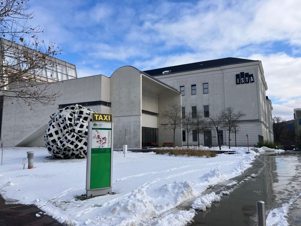White campus building with a sign for a taxi and snow on the ground