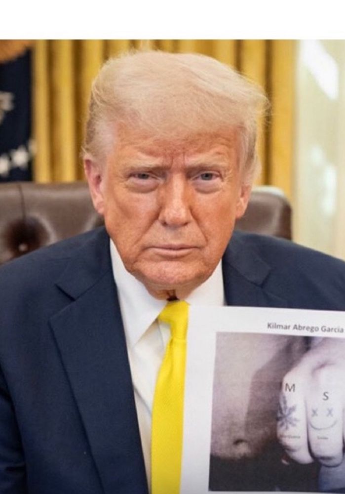 donald trump holding up a propaganda image about kilmar abrego garcia’s tattoos. trump looks visibly exhausted 