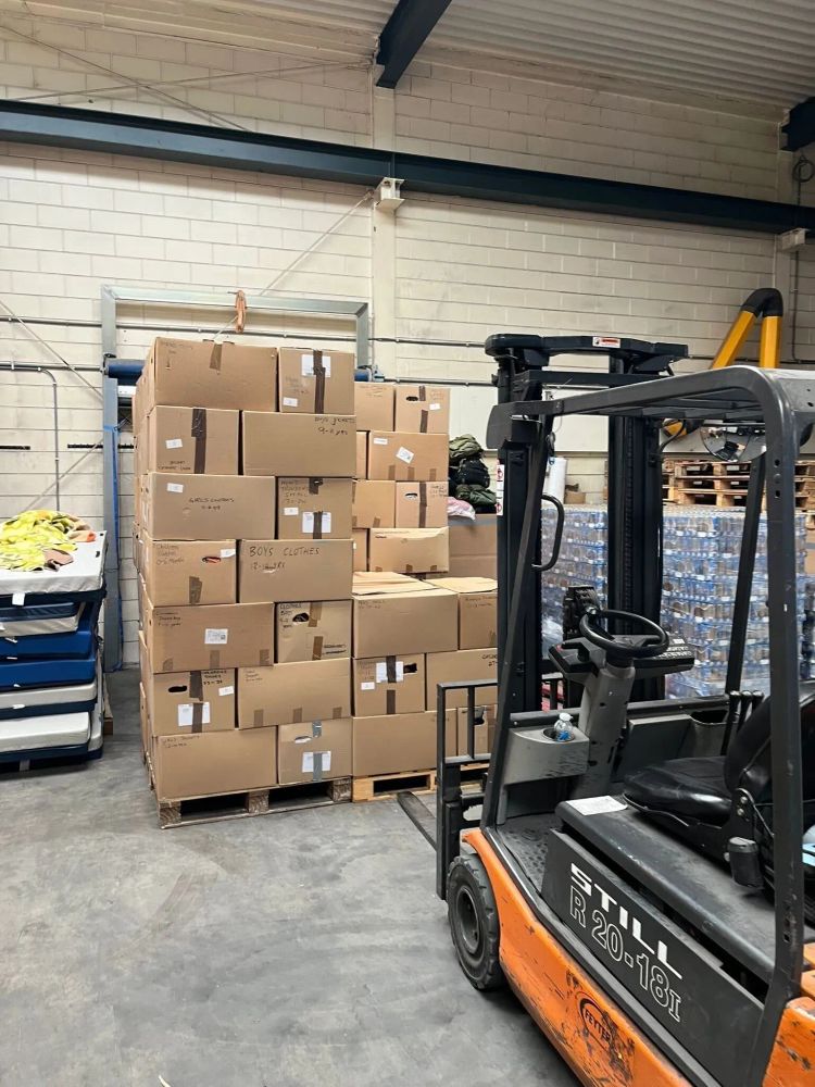 A photo of a number of boxes sitting on a pallet next to a forklift