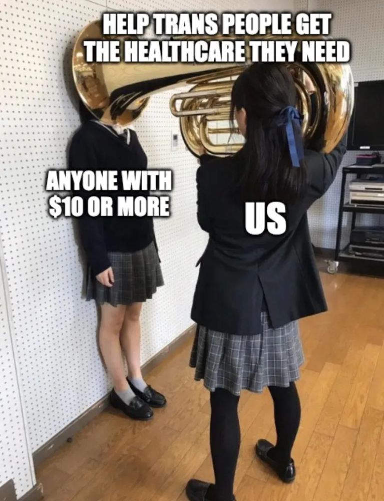 A girl in her school uniform holds a tuba to the face of her classmate.