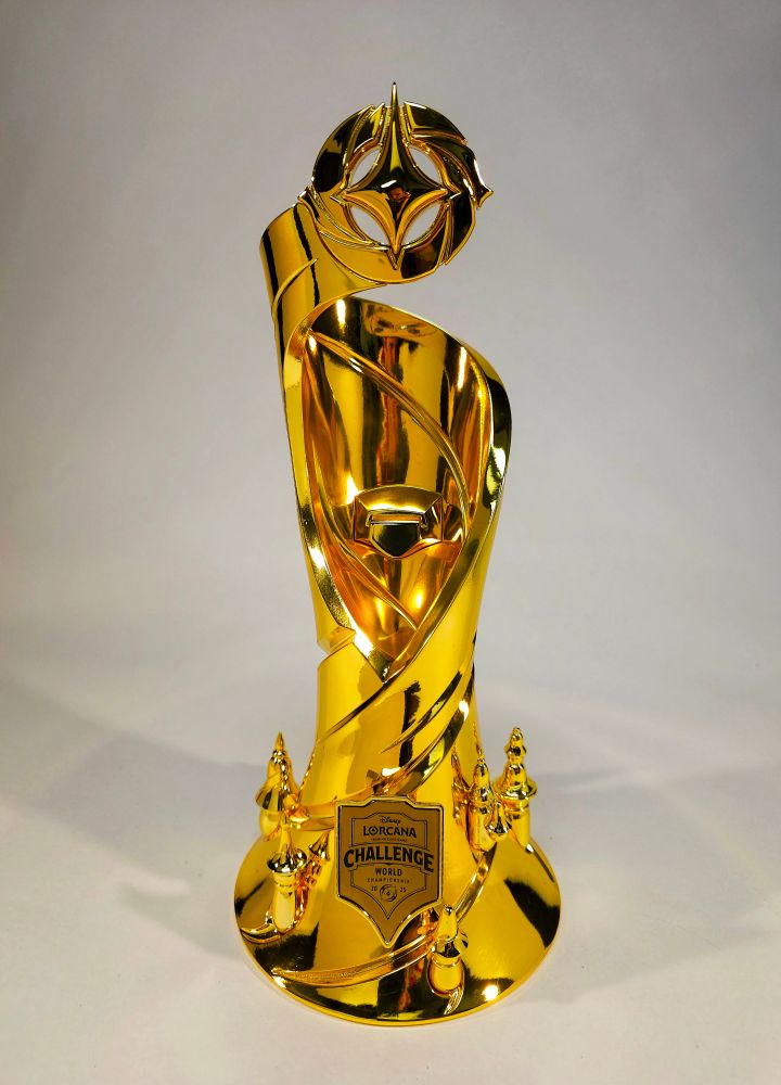 A brilliantly mirrored gold trophy for Disney's Lorcana, decorated with an Aladdin themed filigree.
