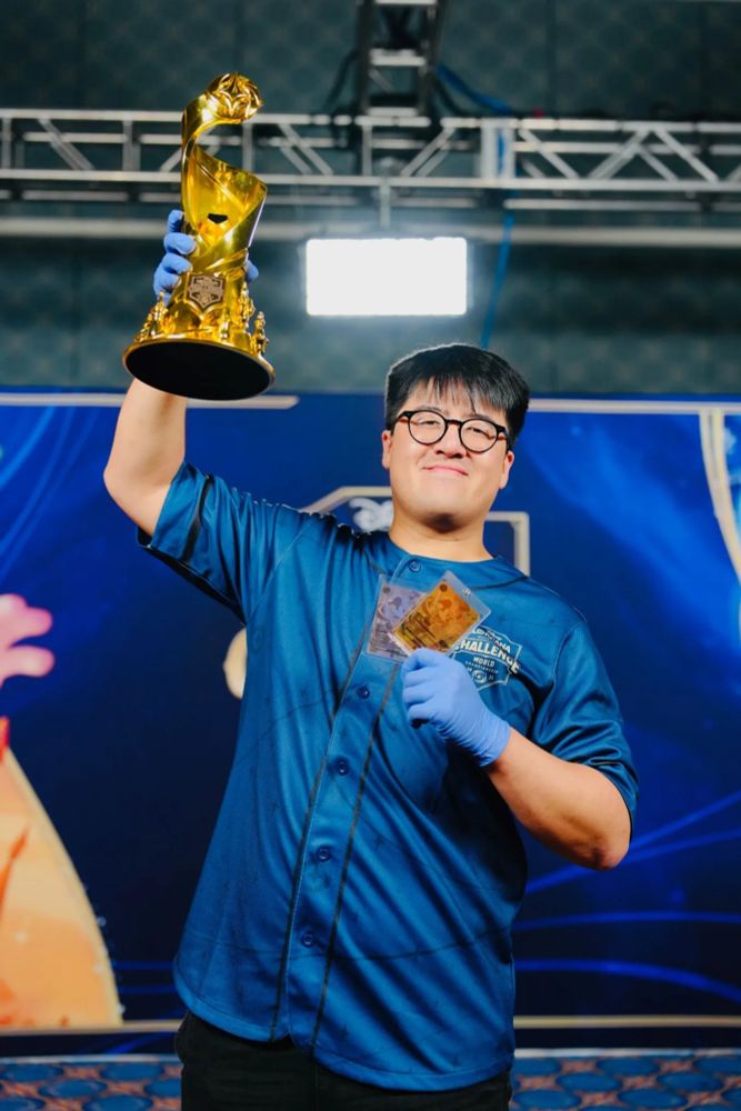 The player that won a Lorcana trophy holding up their gold chrome trophy and matching custom guilded card. 