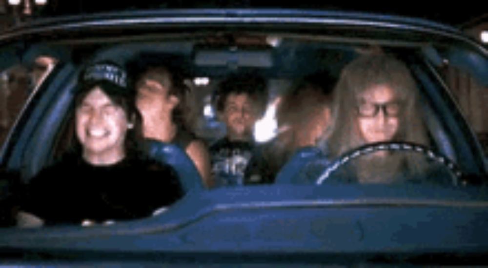 a group of people are sitting in a blue car and smiling .