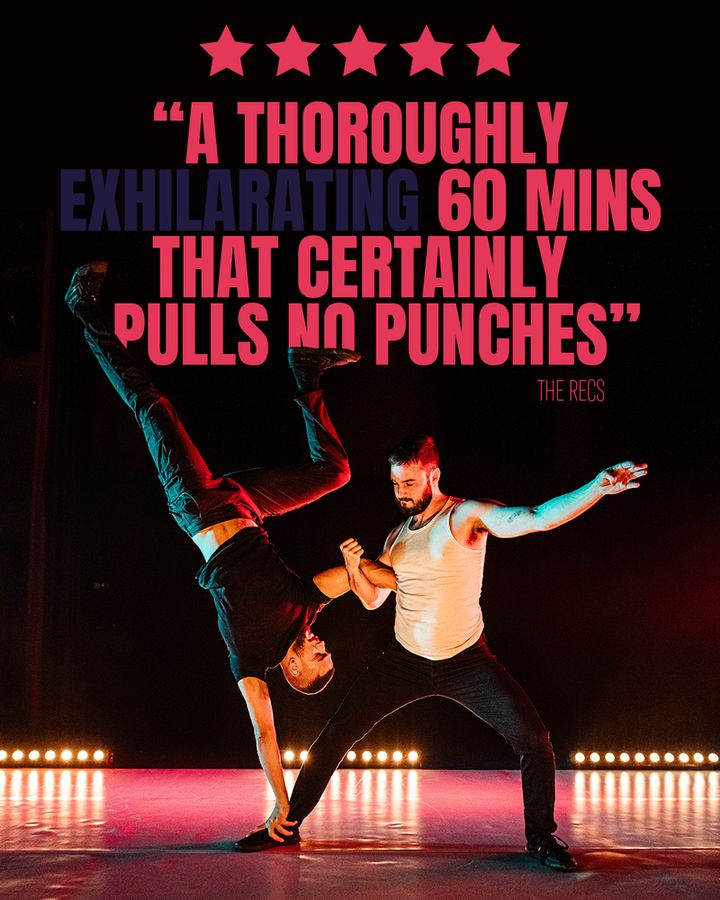 Big red and blue text reads: ***** "A thoroughly exhilarating 60 minites that certainly pulls no punches" - The Recs. Below there are two male-presenting performers on a white stage lit with red and blue. One is upside down in a handstand using the other as a base, their arms linked, leaning away from each other
