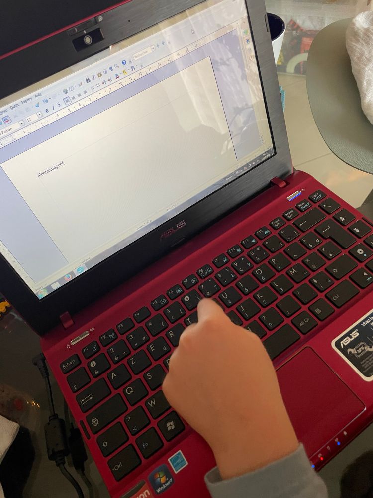 Une petite main qui tape sur le clavier du pc portable. 