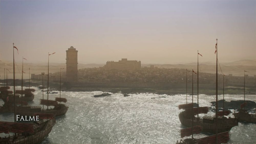 A screenshot from The Wheel of Time Season 2, Episode 5 used in the fan edit film "The Dragon Reborn". It shows a shot of a fleet of ships in the ocean, in the background is a city with a prominent tower and fort. In the lower left is a caption titled "Falme".