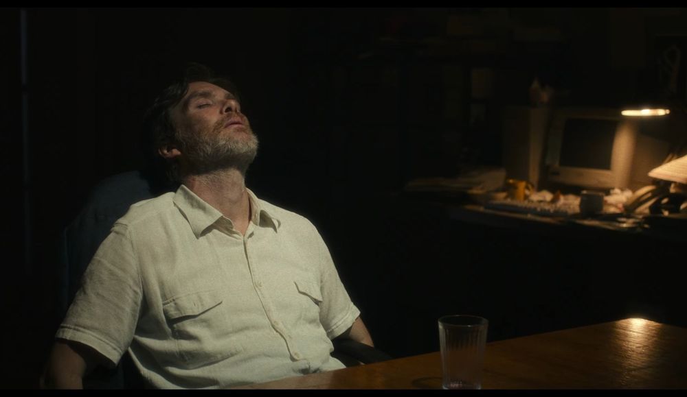 Capture d'écran du film Steve. On y voit le personnage principal, Steve, joué par Cillian Murphy, portant une chemise blanche, affalé sur une chaise, la tête en arrière et les yeux fermés. Il est dans une pièce sombre, le soir, éclairée par une petite lampe de bureau.
