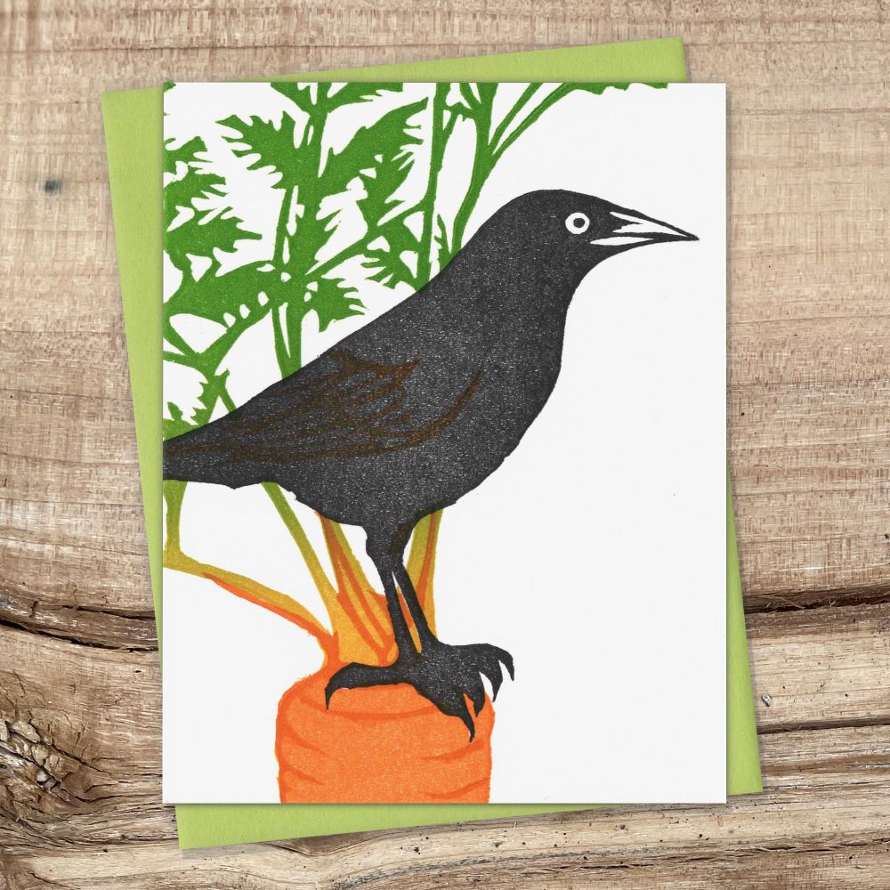 Grackle standing on a carrot amidst the greens. Original block print greeting card.