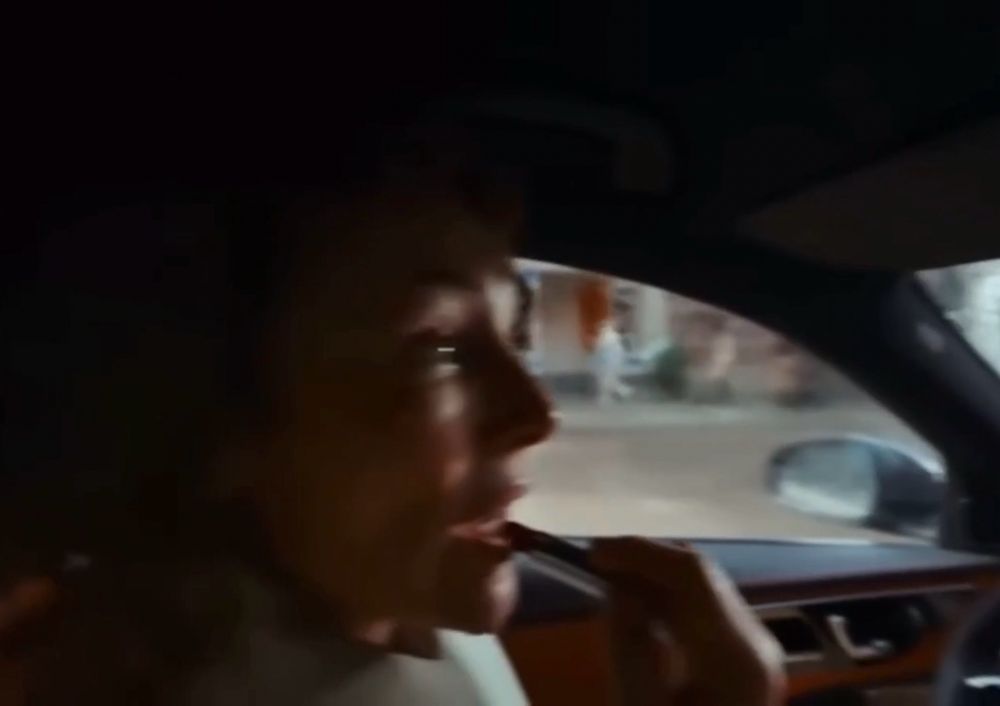 A still frame from the video which shows the woman behind the wheel putting on lipstick using the rear view mirror.