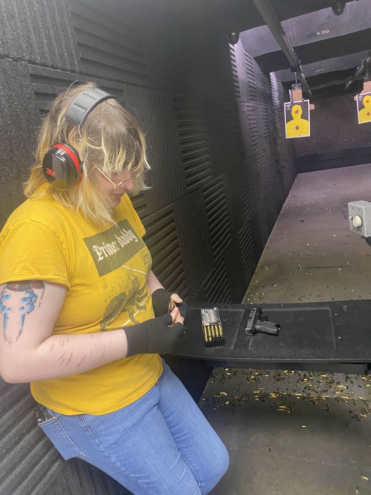 atty at a firing range, leaning against the wall filling a magazine 