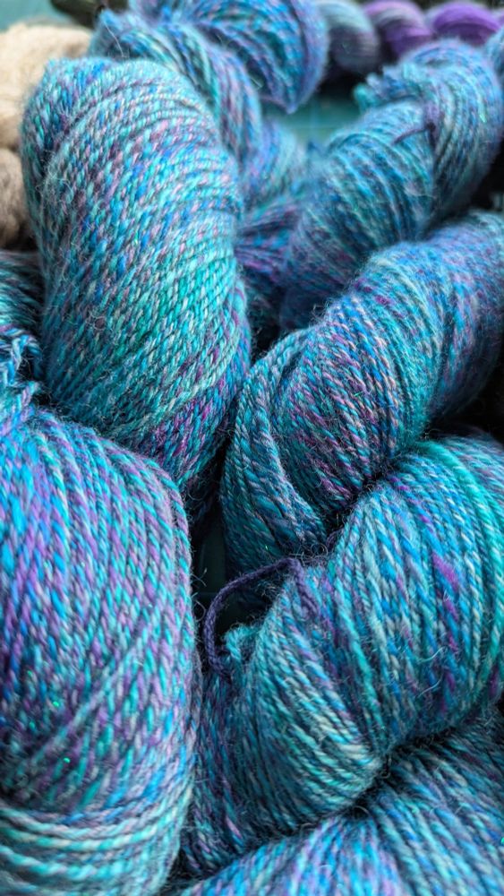 Closeup of the two skeins of blue and purple fingering weight yarn.
