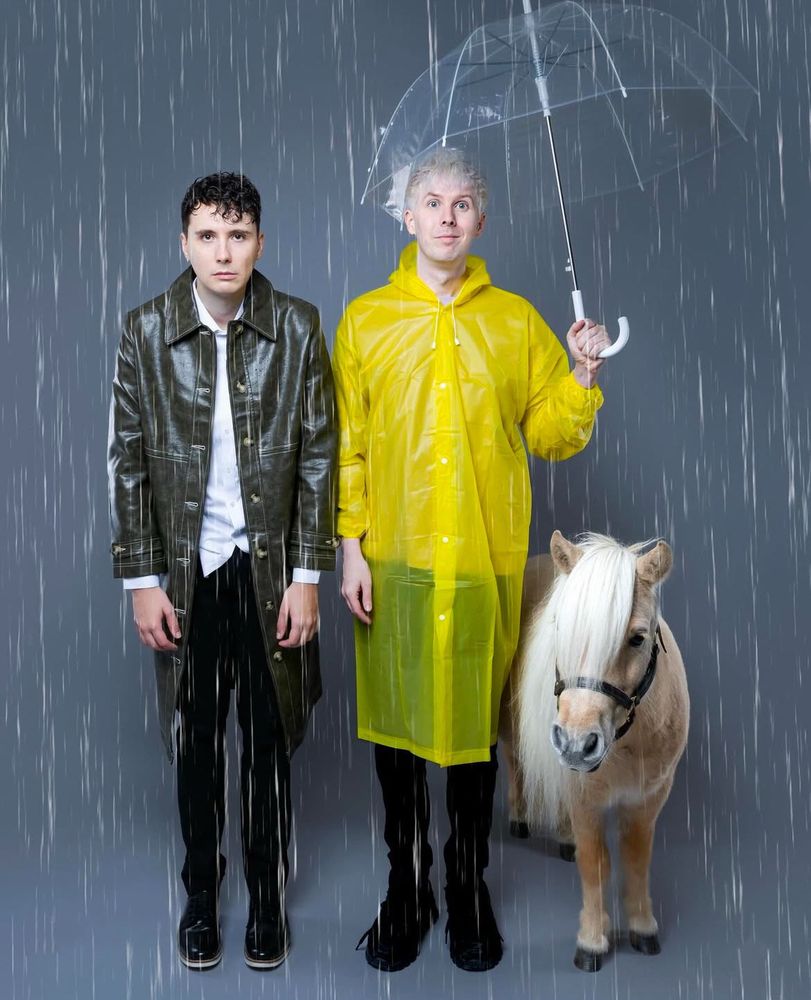 dan and phil in the rain posing with a horse, from their 2025 calendar