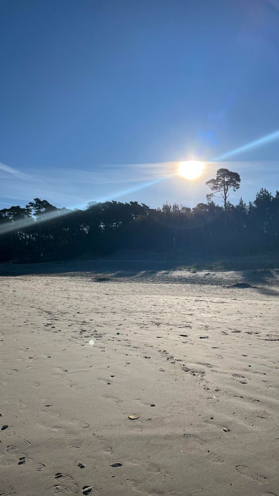 Słońce wschodzi na bezchmurnym niebie ponad skarpą i plażą w #Ustka