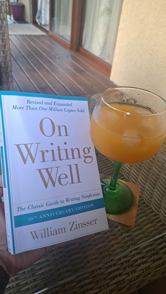 Zdjęcie przedstawia ksiazkę:
"On Writing Well"

The Classic Guide to Writing Nonfiction
30 TH ANNIVERSARY EDITION

Autorstwa Williama Zinssera.

Obok książki stoi pomarańczowy koktajl, bo to wakacje