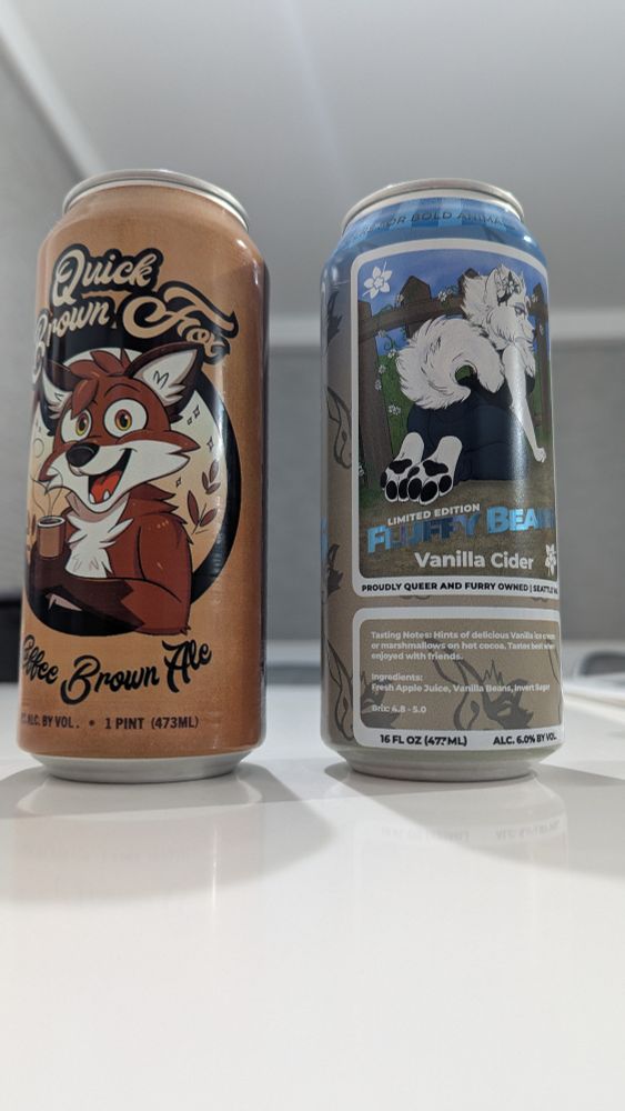 Two cans of beer sitting on a white counter. One is a can of quick brown fox coffee stout from vulpine taproom, and the other is a can of fluffy beans vanilla cider from slightly furry taproom.