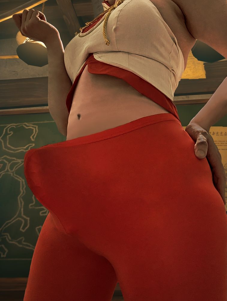 Natalie in a dressed down version of her Purah cosplay, without the skirt and big coat, so that her top and leggings remain. The focus of the picture is the bulge of her erect cock, stretching against the hem of the leggings and pushing it away from her body. The picture has been edited, with a background taken from Tears of the Kingdom, that being Purah's lab, and the lighting coloration has been changed to match.