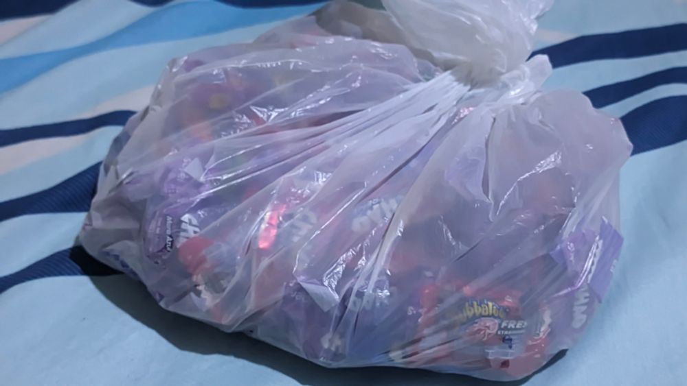 A plastic bag lying on a blue bed, full candy (there are 80 inside).