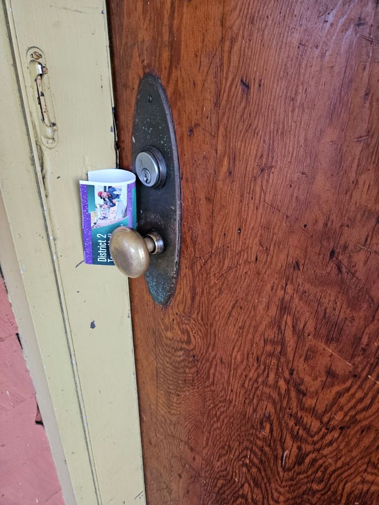 A rolled up flier left at a person's door, which invites the recipients to a District 2 town hall in Lloyd Center at 5:30 pm on Friday 12/19.