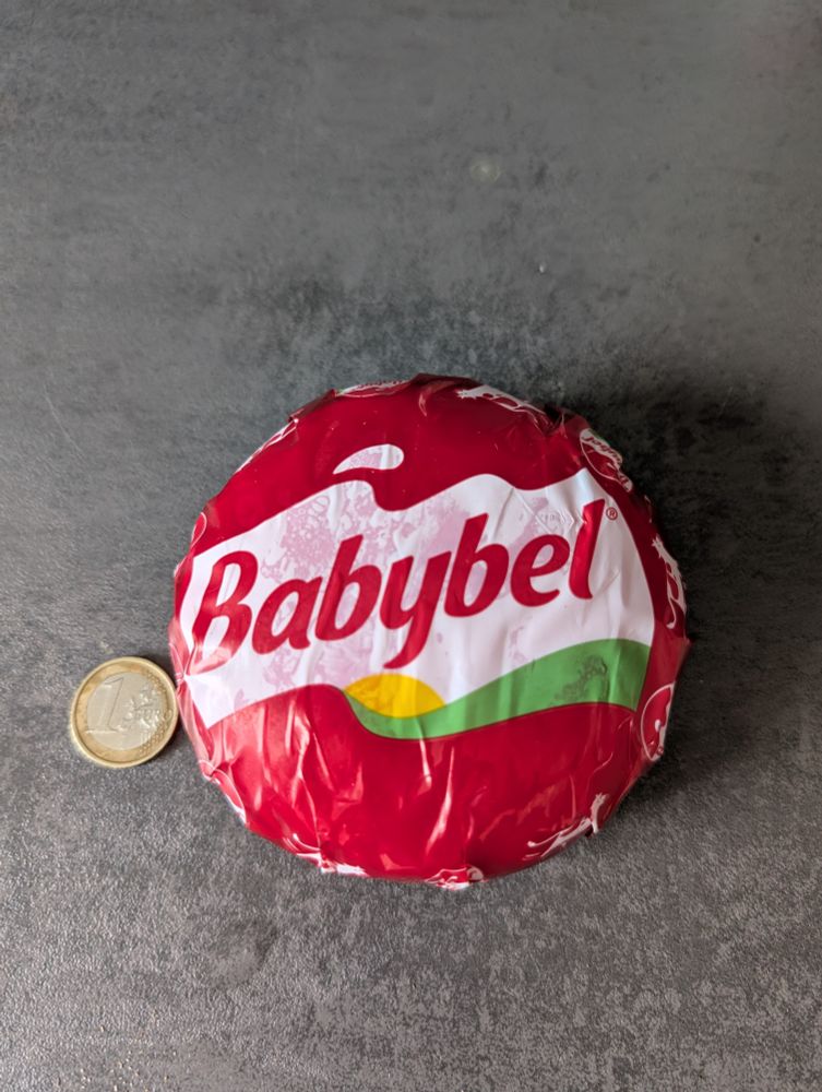 A giant babybel next to a 1 euro coin as proof of size 