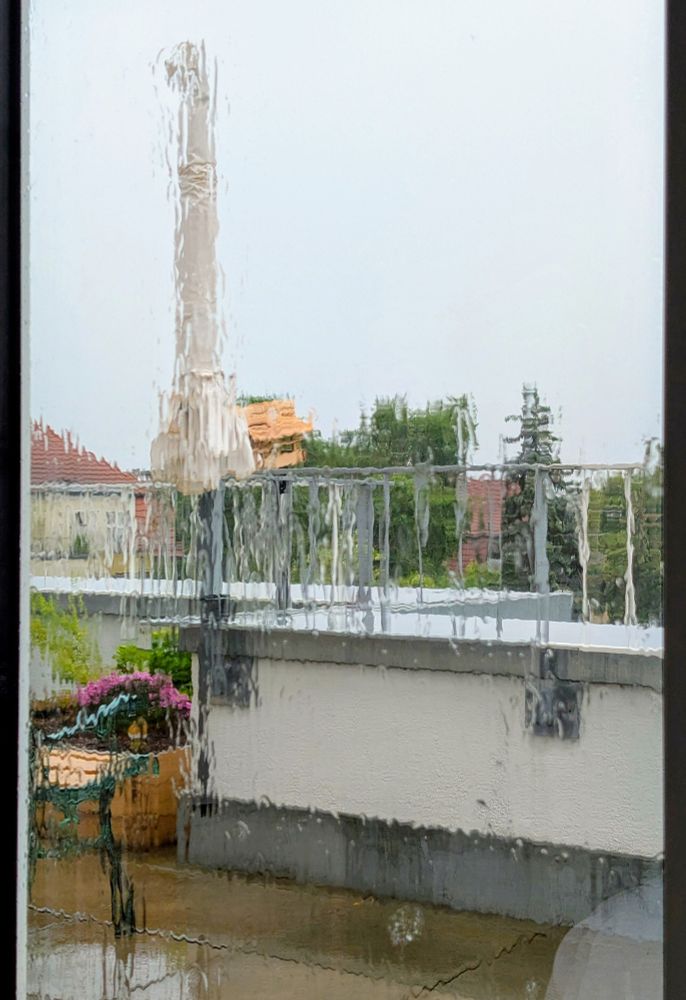 A rain-drenched window looking into a balcony 