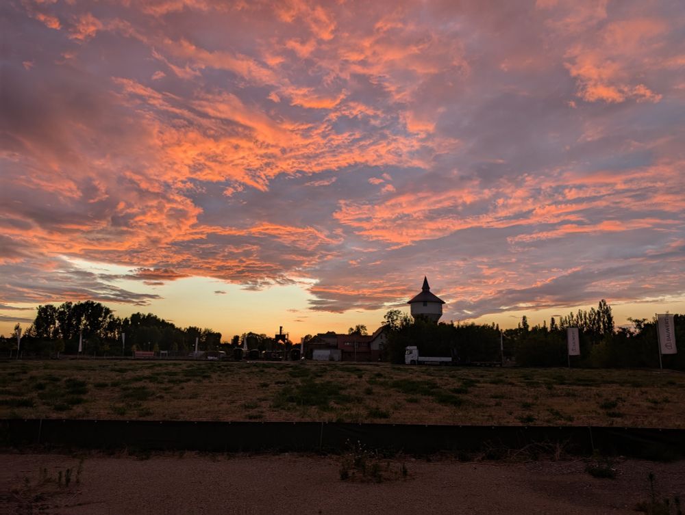 A vivid, cloudy sunset with a low tower in the foreground 