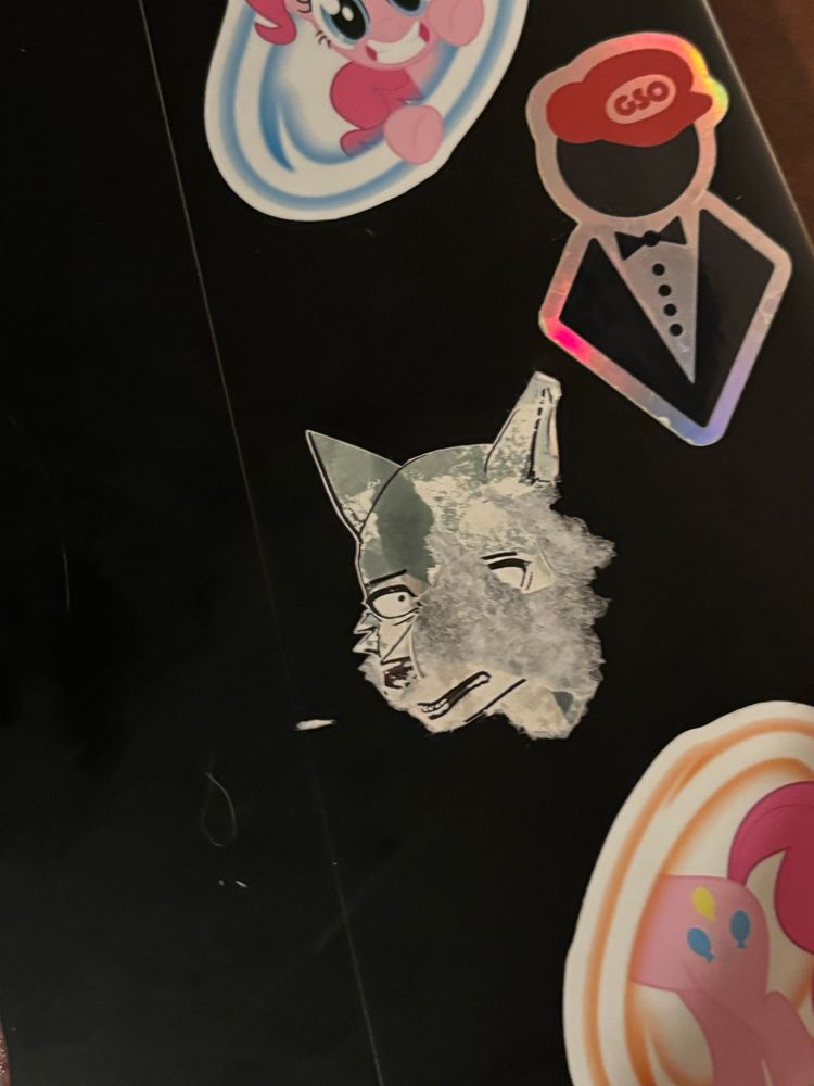 The back of my laptop, specifically focused on my Legoshi sticker, which has been partially ripped off from cleaning up the cat puke.