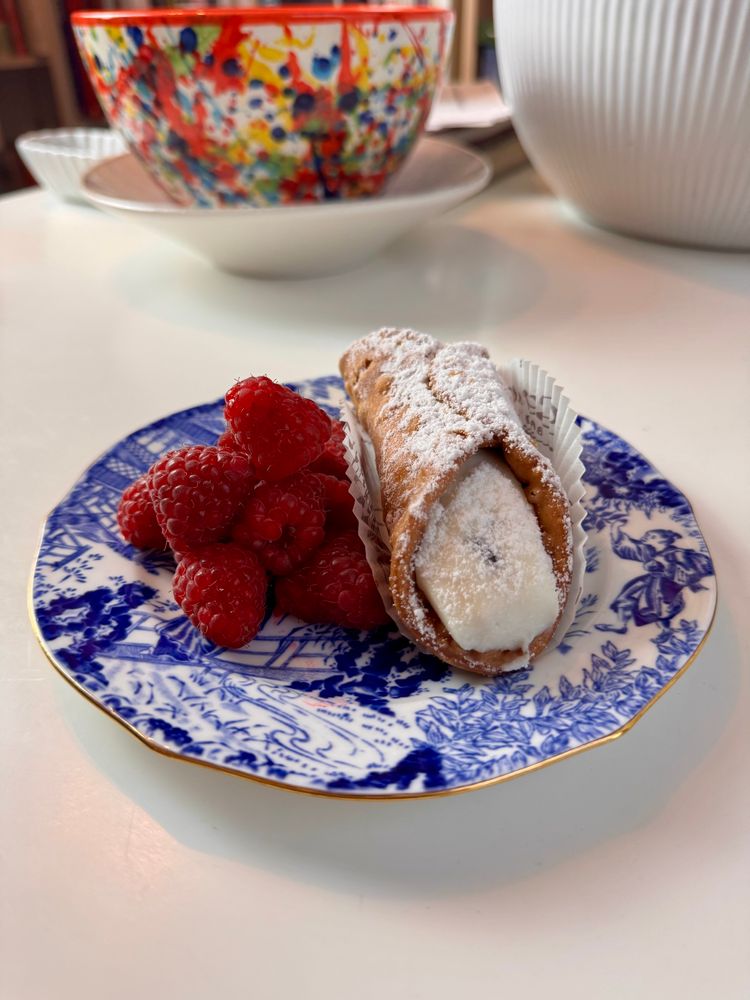 A sugar-dusted cannoli with sweet ricotta filling and red, sweet Ontario raspberries.