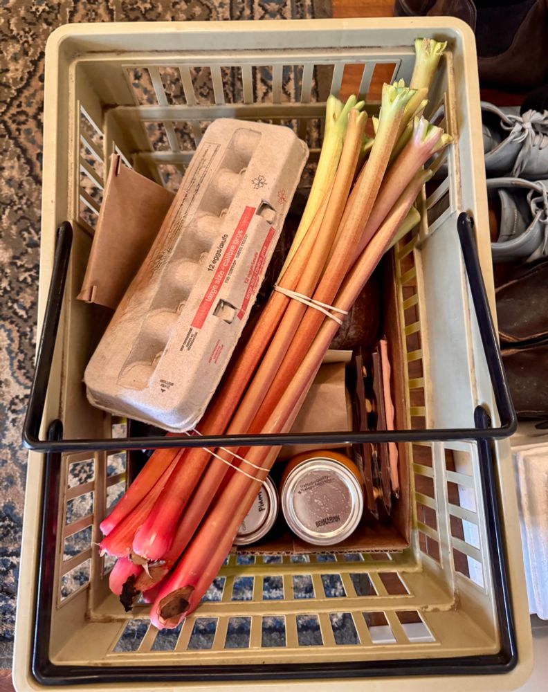 An old LCBO basket filled with rhubarb, eggs, sourdough bread, preserves, and baked goods.