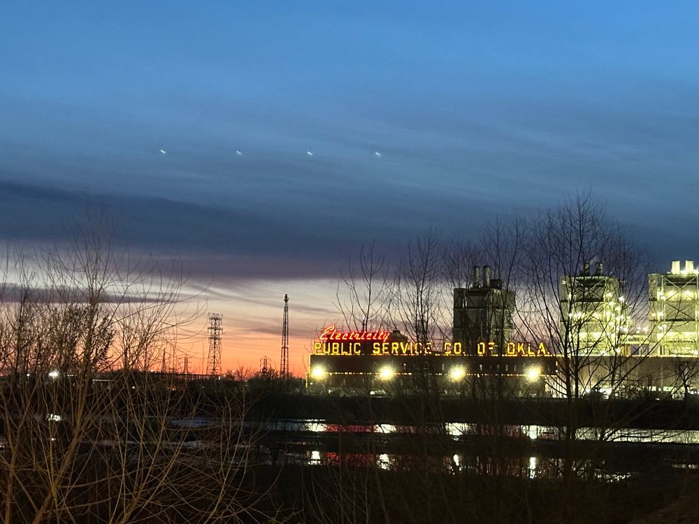 Sunset over the Arkansas river with the electricity public service of tulsa sign in the background. It’s a beautiful sunset with lots of colors.
