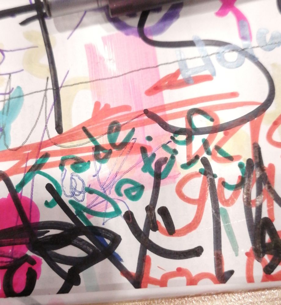 Text written on a vandalized sheet of white paper that says "Jade Nation >:)" on teal green ink