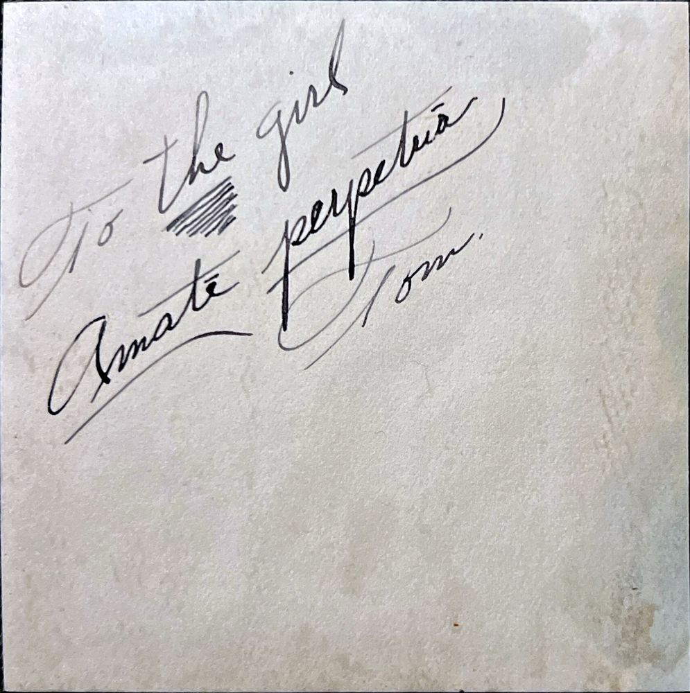Handwritten text in black ink on the back of the photo. It reads: To the girl. Amate perpetua. Tom. 

 (“The” is underlined heavily for emphasis). 