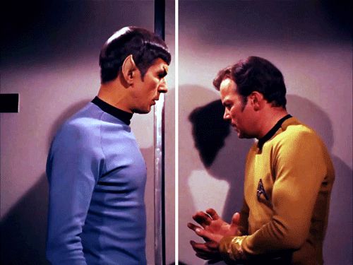 Spock and Kirk from the tv show Star Trek TOS standing next to each other. Kirk seems to be nervous, Spock is touching him. 