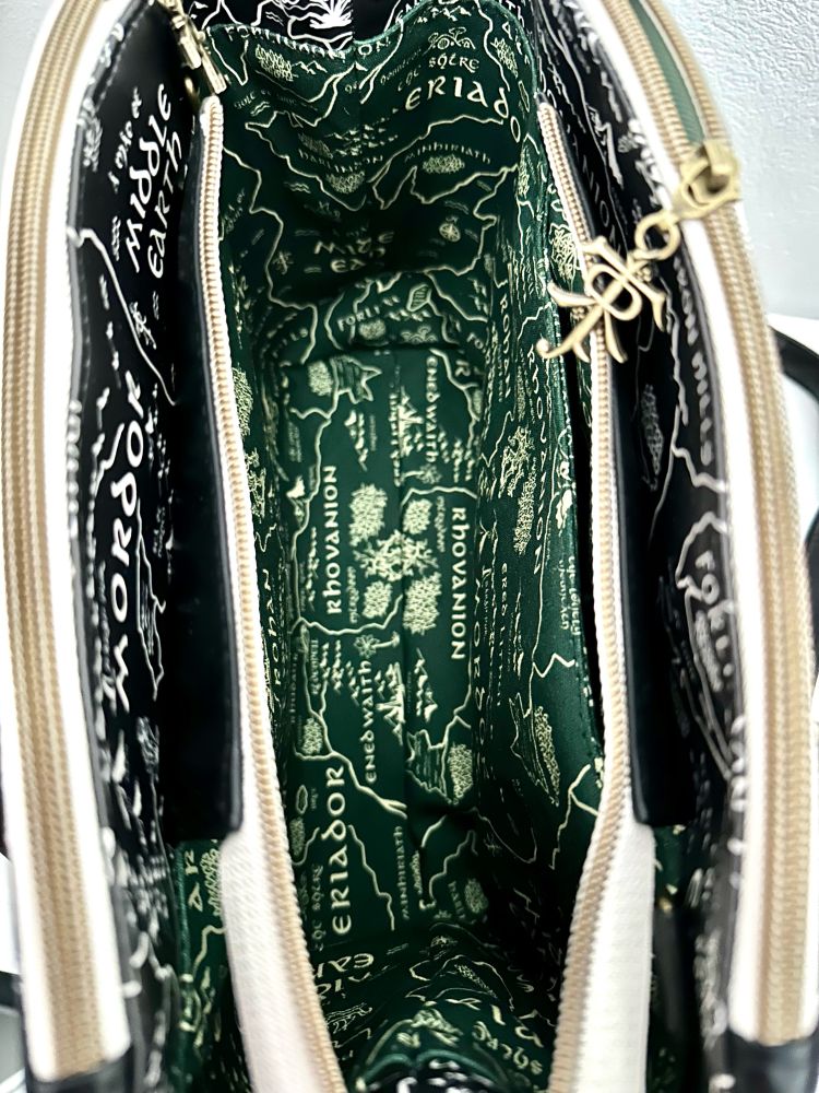 The inside of the bag. The liner fabric also shows the map from Lord of The Rings, printed light green on dark green. One of the zipper pulls is bronze and shows the JRRT monogram. 